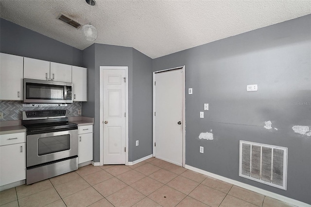 979 Mayfair St, Eustis, FL 32726 - kitchen with stainless steel appliances, decorative backsplash, white cabinets, light tile patterned flooring, and a textured ceiling