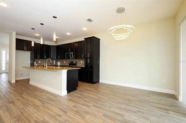 1222 Castlevecchio Loop, Orlando, FL 32825 - kitchen featuring black range with electric cooktop, light stone countertops, backsplash, stainless steel microwave, and a chandelier