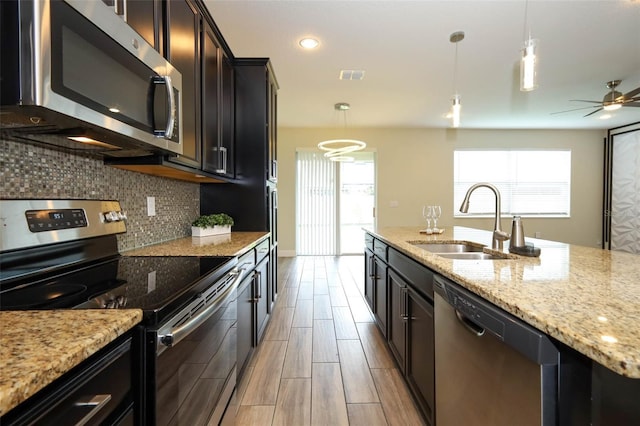 1222 Castlevecchio Loop, Orlando, FL 32825 - kitchen featuring appliances with stainless steel finishes, backsplash, light stone counters, hanging light fixtures, and ceiling fan