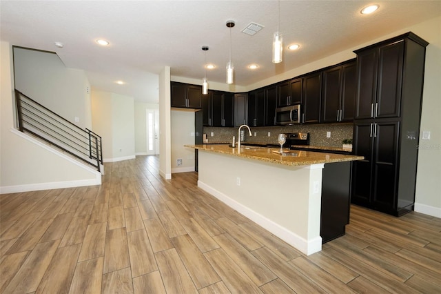 1222 Castlevecchio Loop, Orlando, FL 32825 - kitchen with stainless steel microwave, electric range oven, light wood-style flooring, light stone countertops, and decorative backsplash