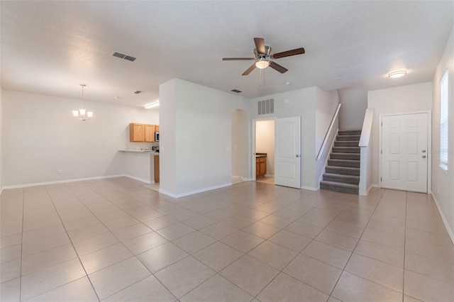 1129 Royal Ridge Dr, Davenport, FL 33896 - unfurnished living room featuring stairway, ceiling fan, light tile patterned floors, arched walkways, and a textured ceiling