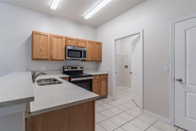 1129 Royal Ridge Dr, Davenport, FL 33896 - kitchen featuring stainless steel appliances, light tile patterned floors, a peninsula, light stone counters, and brown cabinetry
