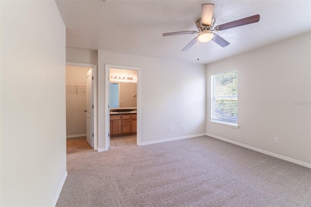 1129 Royal Ridge Dr, Davenport, FL 33896 - unfurnished bedroom with light carpet, a spacious closet, a textured ceiling, ensuite bathroom, and a closet