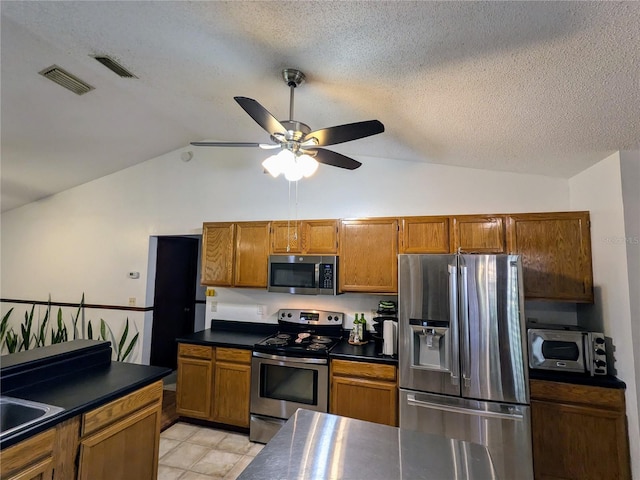 3021 Norvell Ct, Deltona, FL 32738 - kitchen featuring appliances with stainless steel finishes, dark countertops, lofted ceiling, ceiling fan, and brown cabinets