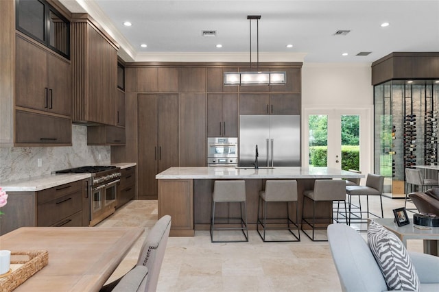 3426 Cocard Ct, Windermere, FL 34786 - kitchen with high end appliances, a kitchen bar, a kitchen island with sink, dark brown cabinets, and crown molding
