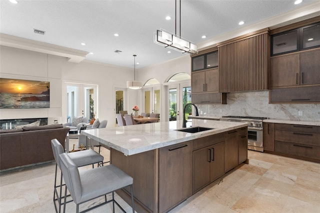 3426 Cocard Ct, Windermere, FL 34786 - kitchen with high end range, an island with sink, ornamental molding, decorative backsplash, and a breakfast bar