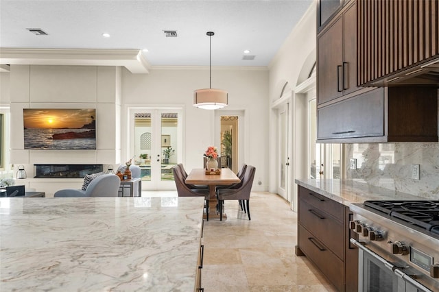 3426 Cocard Ct, Windermere, FL 34786 - kitchen with backsplash, light stone countertops, dark brown cabinets, crown molding, and decorative light fixtures