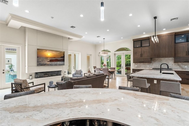 3426 Cocard Ct, Windermere, FL 34786 - kitchen with french doors, ornamental molding, tasteful backsplash, recessed lighting, and light stone countertops