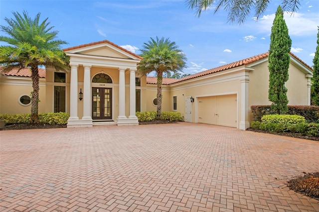 3426 Cocard Ct, Windermere, FL 34786 - greek revival house with french doors, decorative driveway, a garage, stucco siding, and a tiled roof