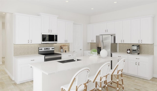 1993 Beach Ter, Celebration, FL 34747 - kitchen with appliances with stainless steel finishes, a kitchen island with sink, backsplash, light wood-style floors, and a breakfast bar
