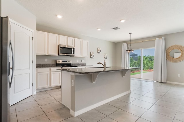 6808 Cranes Roost Rd, Harmony, FL 34773 - kitchen featuring appliances with stainless steel finishes, dark stone counters, a breakfast bar area, light tile patterned floors, and white cabinetry