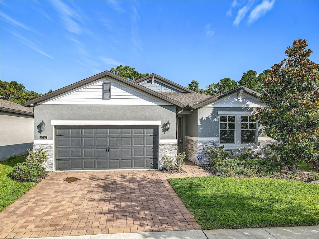 2247 Marsh Sedge Ln, Winter Park, FL 32792 - ranch-style home featuring stone siding, stucco siding, an attached garage, and decorative driveway