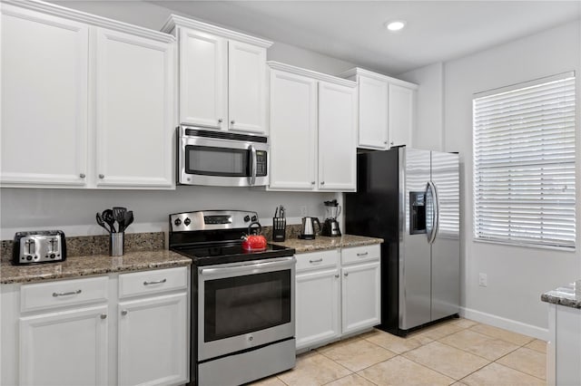 9023 Shadow Mountain St, Davenport, FL 33896 - kitchen with appliances with stainless steel finishes, white cabinets, light tile patterned flooring, light stone countertops, and recessed lighting