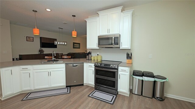 4858 Magnetite Loop, Mount Dora, FL 32757 - kitchen with stainless steel appliances, light wood-style floors, a peninsula, white cabinetry, and recessed lighting