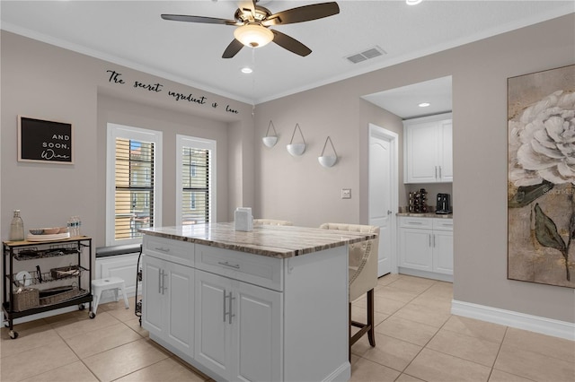 3508 Porta Romano Way, Lake Mary, FL 32746 - kitchen with light tile patterned floors, white cabinetry, a ceiling fan, a center island, and ornamental molding