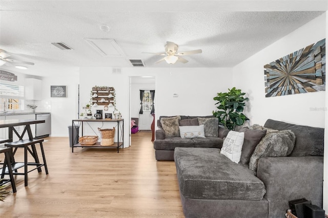 5141 Mallet Dr, Port Richey, FL 34668 - living room with a ceiling fan, light wood-style flooring, a textured ceiling, and attic access