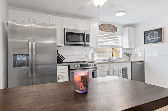 5141 Mallet Dr, Port Richey, FL 34668 - kitchen featuring stainless steel appliances, white cabinets, backsplash, ceiling fan, and a textured ceiling