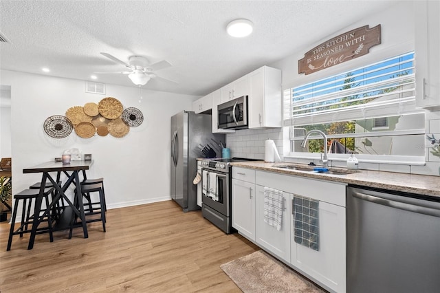 5141 Mallet Dr, Port Richey, FL 34668 - kitchen featuring stainless steel appliances, backsplash, a ceiling fan, white cabinetry, and a textured ceiling