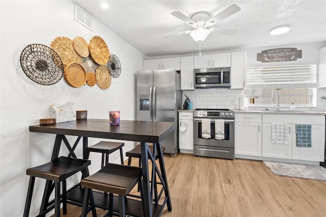 5141 Mallet Dr, Port Richey, FL 34668 - kitchen with appliances with stainless steel finishes, tasteful backsplash, a textured ceiling, light wood-style flooring, and ceiling fan