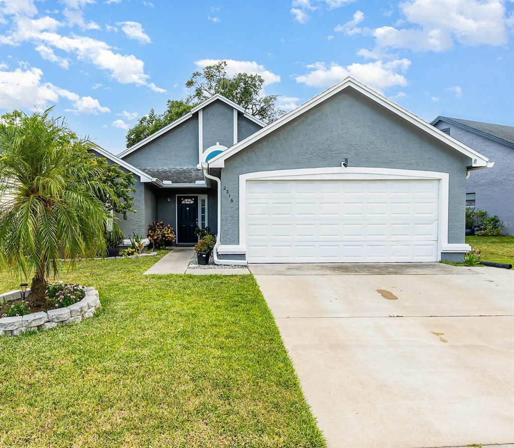2216 Grand Tree Ct, Lake Mary, FL 32746 - view of front of property featuring stucco siding, an attached garage, driveway, and a front yard