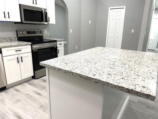 926 Freshmeadow Ct, Apopka, FL 32703 - kitchen featuring appliances with stainless steel finishes, light wood-style flooring, arched walkways, and white cabinets