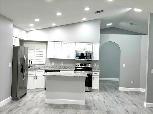 926 Freshmeadow Ct, Apopka, FL 32703 - kitchen featuring appliances with stainless steel finishes, vaulted ceiling, white cabinetry, a center island, and light stone countertops