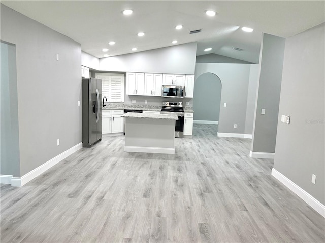 926 Freshmeadow Ct, Apopka, FL 32703 - kitchen with appliances with stainless steel finishes, a center island, white cabinets, arched walkways, and light wood-style floors
