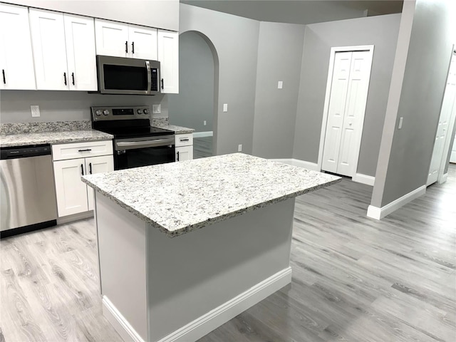 926 Freshmeadow Ct, Apopka, FL 32703 - kitchen featuring stainless steel appliances, arched walkways, light wood-style flooring, and white cabinetry