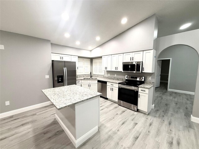 926 Freshmeadow Ct, Apopka, FL 32703 - kitchen with appliances with stainless steel finishes, arched walkways, white cabinets, light stone countertops, and a kitchen island
