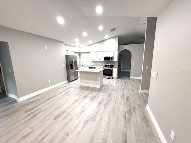 926 Freshmeadow Ct, Apopka, FL 32703 - kitchen with stainless steel appliances, white cabinets, arched walkways, light countertops, and lofted ceiling