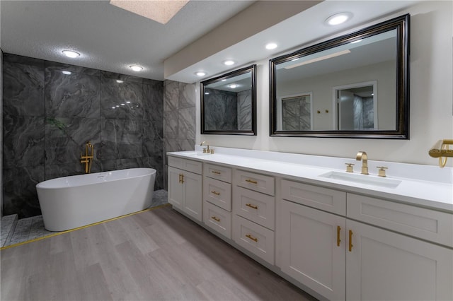 6019 Crystal View Dr, Orlando, FL 32819 - full bathroom with double vanity, a soaking tub, wood finished floors, a textured ceiling, and tile walls