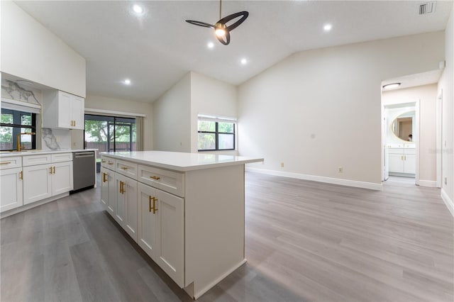 6019 Crystal View Dr, Orlando, FL 32819 - kitchen featuring stainless steel dishwasher, light countertops, vaulted ceiling, a kitchen island, and white cabinetry