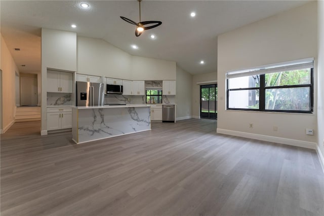 6019 Crystal View Dr, Orlando, FL 32819 - kitchen featuring appliances with stainless steel finishes, white cabinetry, light countertops, light wood finished floors, and high vaulted ceiling