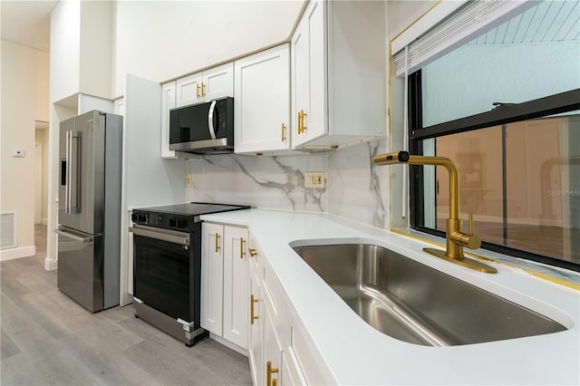 6019 Crystal View Dr, Orlando, FL 32819 - kitchen with appliances with stainless steel finishes, light wood-type flooring, white cabinetry, and light countertops