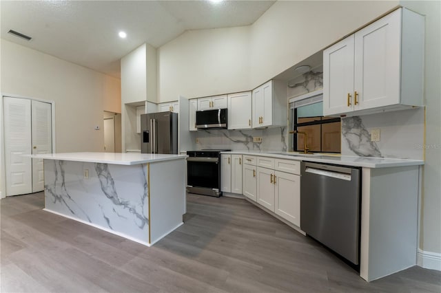 6019 Crystal View Dr, Orlando, FL 32819 - kitchen with appliances with stainless steel finishes, white cabinetry, backsplash, high vaulted ceiling, and a center island