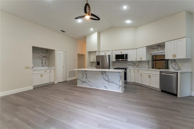 6019 Crystal View Dr, Orlando, FL 32819 - kitchen with stainless steel appliances, high vaulted ceiling, white cabinets, a kitchen island, and light wood-type flooring