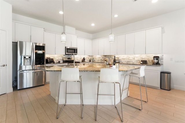 15448 Murcott Blossom Blvd, Winter Garden, FL 34787 - kitchen featuring appliances with stainless steel finishes, decorative backsplash, light wood-style floors, a breakfast bar area, and recessed lighting