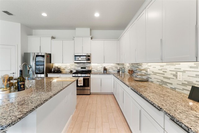 15448 Murcott Blossom Blvd, Winter Garden, FL 34787 - kitchen with stainless steel appliances, white cabinets, decorative backsplash, light stone countertops, and recessed lighting
