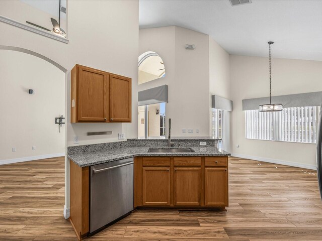 1111 Liberty Hall Dr, Kissimmee, FL 34746 - kitchen featuring dishwasher, high vaulted ceiling, stone countertops, brown cabinets, and light wood finished floors