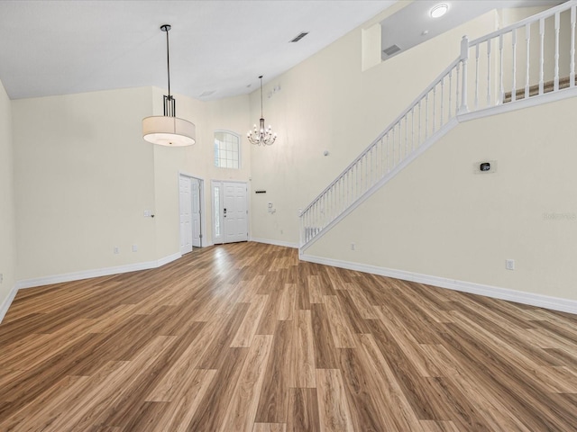 1111 Liberty Hall Dr, Kissimmee, FL 34746 - unfurnished living room with wood finished floors, a towering ceiling, stairs, and a chandelier