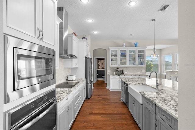 16412 Good Hearth Blvd, Clermont, FL 34711 - kitchen featuring wall chimney range hood, appliances with stainless steel finishes, white cabinets, glass insert cabinets, and a textured ceiling