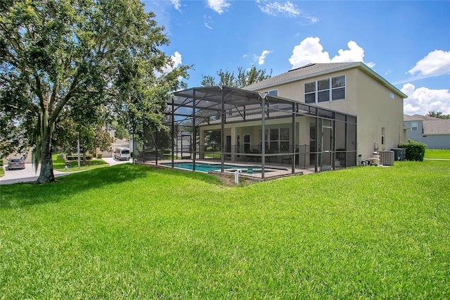 2669 Manesty Ln, Kissimmee, FL 34747 - rear view of house with stucco siding, a lawn, an outdoor pool, and glass enclosure