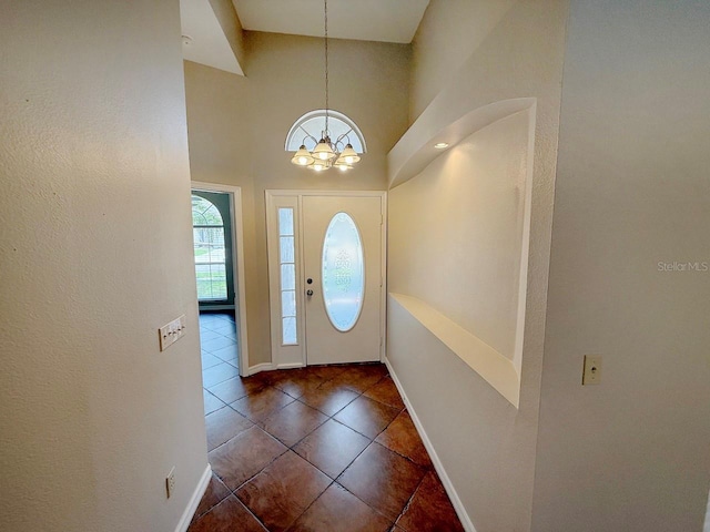 tiled foyer featuring a chandelier and a high ceiling