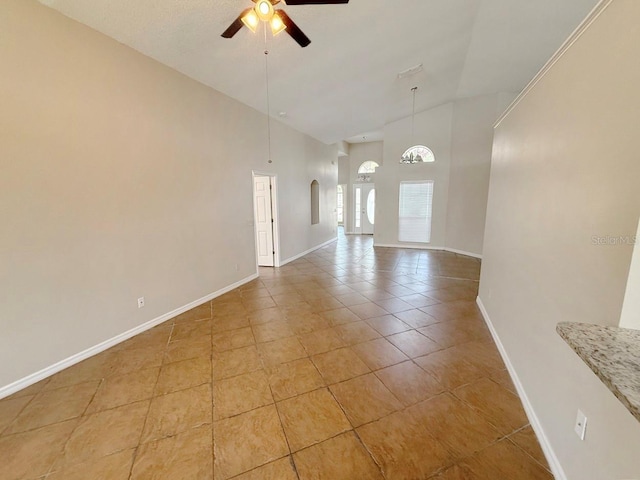spare room with high vaulted ceiling, light tile patterned flooring, ceiling fan, and arched walkways