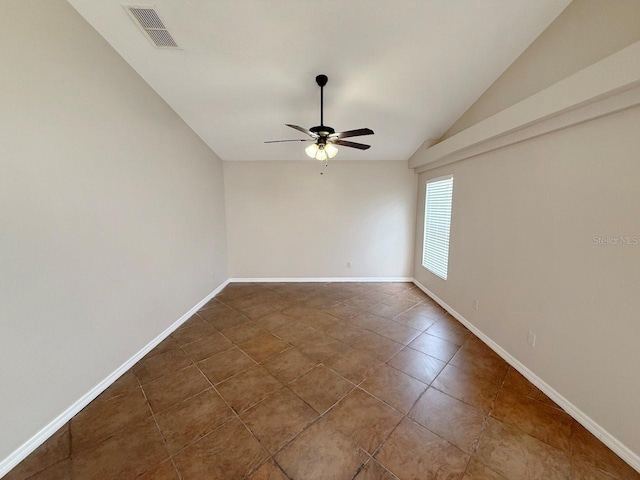 empty room with lofted ceiling, a ceiling fan, and dark tile patterned flooring