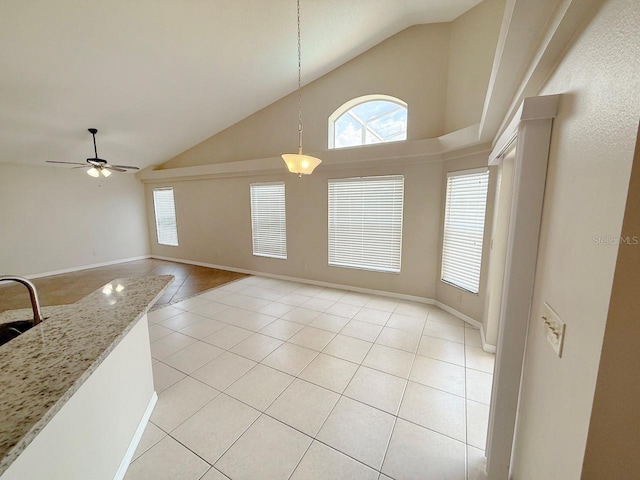 unfurnished dining area featuring light tile patterned floors, high vaulted ceiling, and ceiling fan