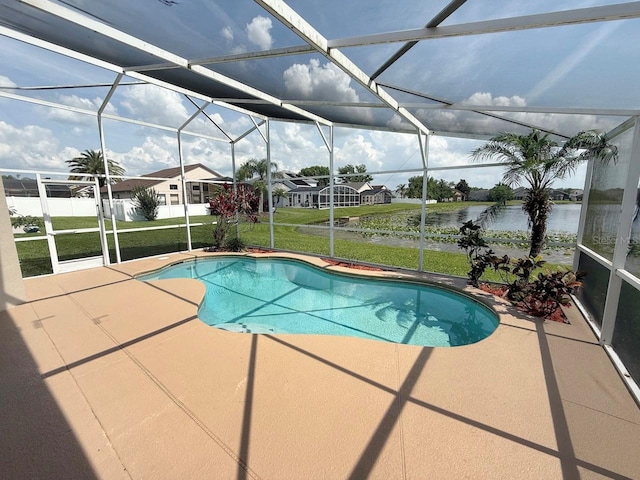 outdoor pool with a water view, a patio area, a lawn, and glass enclosure