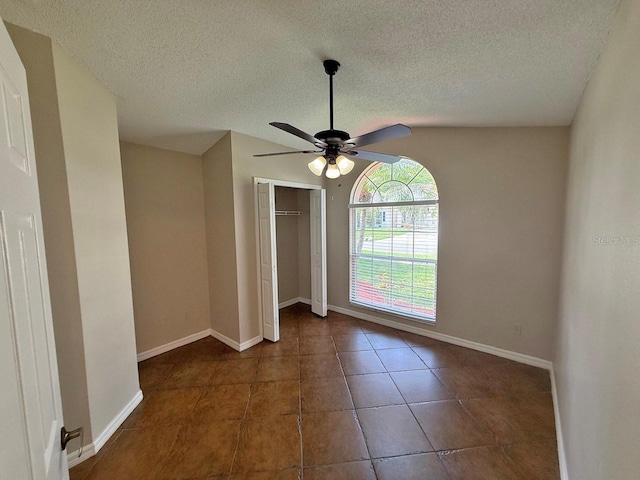 tiled empty room with ceiling fan and a textured ceiling