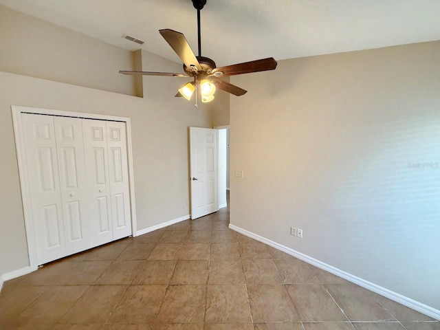 unfurnished bedroom with tile patterned floors, a closet, ceiling fan, and high vaulted ceiling