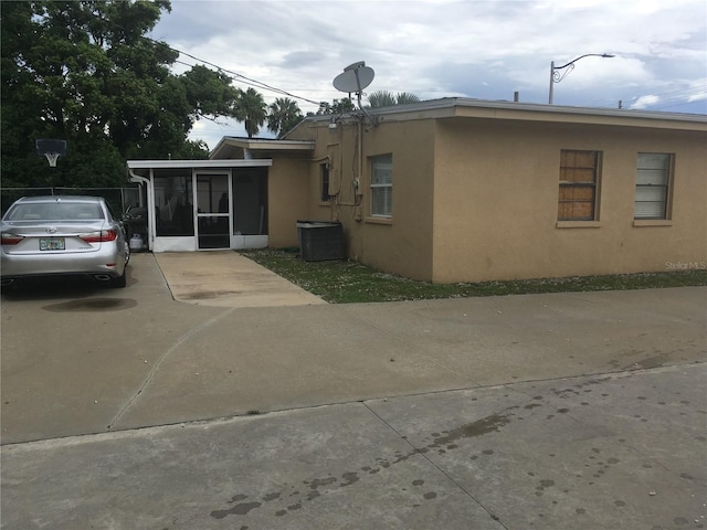 10 S Semoran Blvd S, Orlando, FL 32822 - rear view of property with stucco siding, a sunroom, and driveway